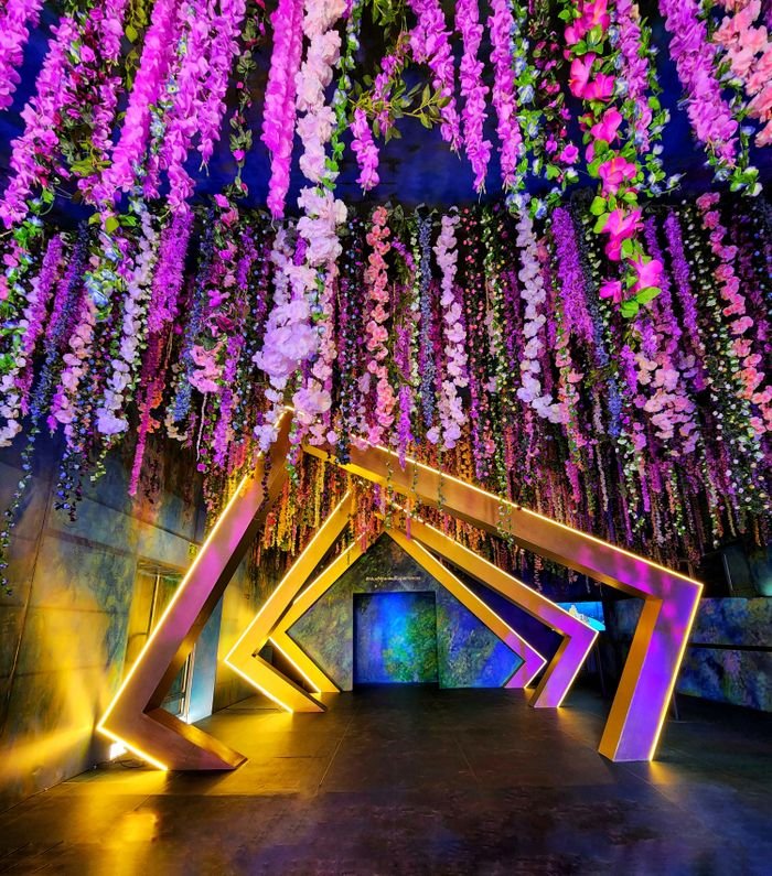 Colorful floral ceiling and illuminated geometric archway create a stunning modern indoor setting.
